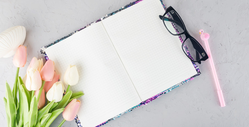 Ανοιχτό journal notebook με γυαλιά, λουλούδια και στυλό